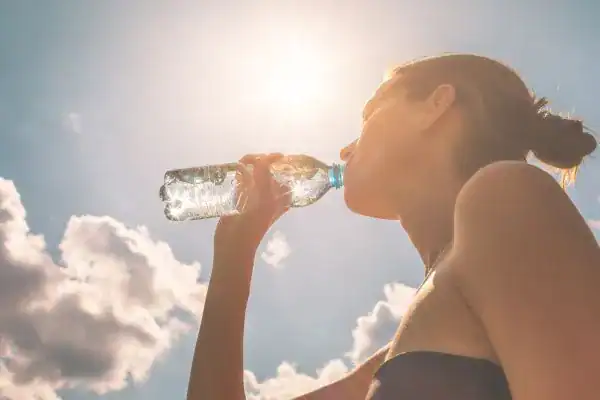 Hydration: The Secret Ingredient for a Toned Stomach and Enhanced Fitness 3 Image of woman drinking water to hydrate Rowley Regis after run.