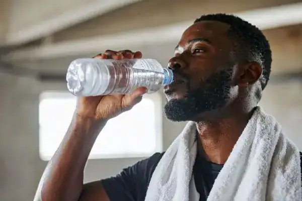 Hydration: The Secret Ingredient for a Toned Stomach and Enhanced Fitness 1 Image of man drinking water to improve hydration Rowley Regis after work out.